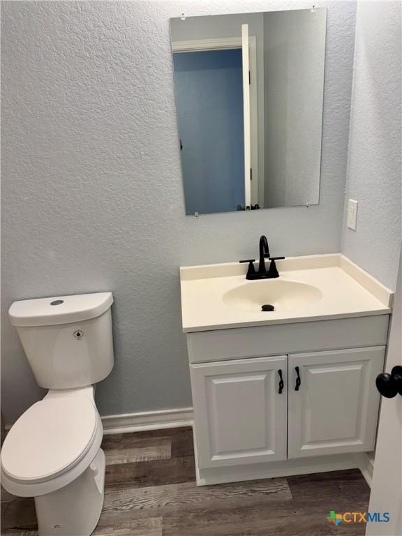 1037 N Guadalupe St, Seguin, TX 78155 - bathroom featuring a textured wall, vanity, wood finished floors, toilet, and baseboards