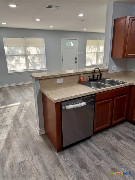 1037 N Guadalupe St, Seguin, TX 78155 - kitchen featuring stainless steel dishwasher, a sink, light wood-style flooring, light countertops, and a peninsula