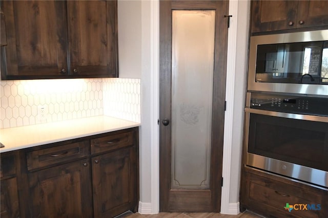 kitchen with appliances with stainless steel finishes, dark brown cabinets, and backsplash