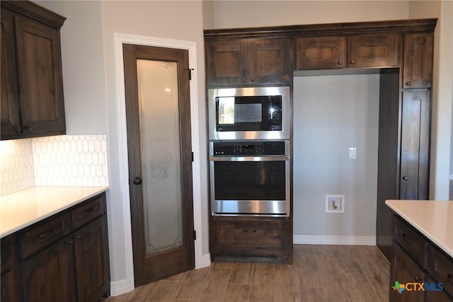 kitchen with stainless steel microwave, decorative backsplash, and dark brown cabinets