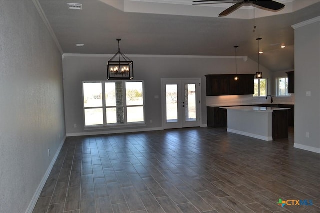 unfurnished living room featuring sink, crown molding, plenty of natural light, and ceiling fan with notable chandelier