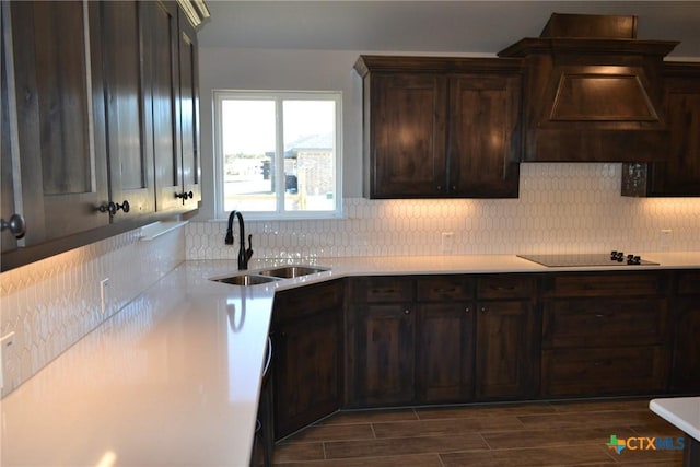 kitchen featuring sink, dark brown cabinets, dark hardwood / wood-style floors, black electric cooktop, and decorative backsplash