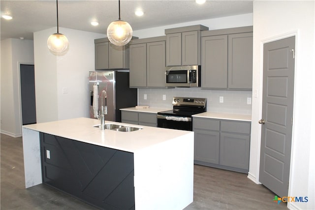 kitchen with stainless steel appliances, sink, hardwood / wood-style flooring, gray cabinets, and hanging light fixtures