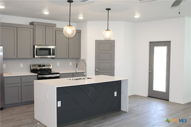 kitchen with gray cabinetry, pendant lighting, sink, and stainless steel appliances