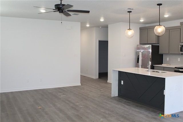 kitchen with gray cabinetry, a center island with sink, sink, stainless steel refrigerator with ice dispenser, and decorative light fixtures