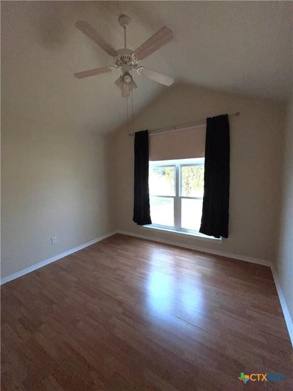 spare room featuring wood finished floors, a ceiling fan, baseboards, and lofted ceiling