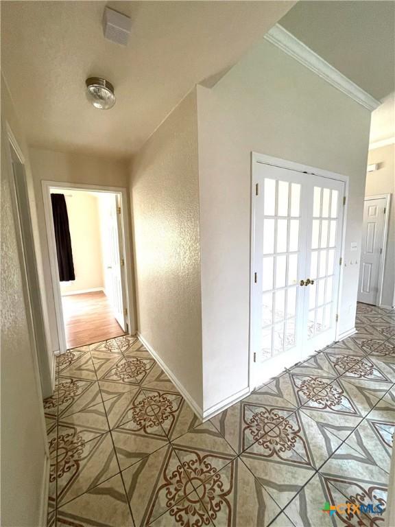 hall featuring light tile patterned flooring, ornamental molding, and baseboards