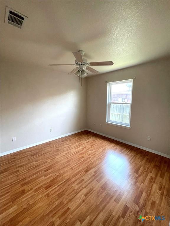 spare room featuring ceiling fan, baseboards, and wood finished floors