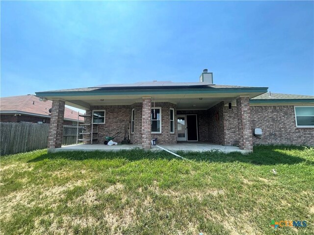 rear view of house featuring a patio, a chimney, and brick siding