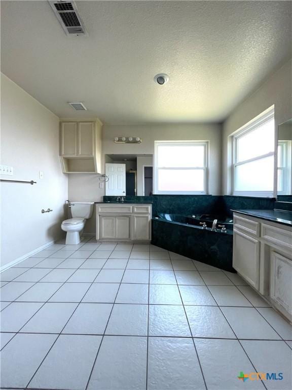 bathroom with plenty of natural light, vanity, a garden tub, and toilet