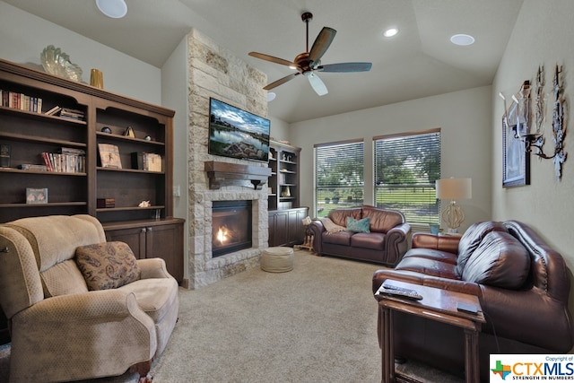 living room featuring a stone fireplace, lofted ceiling, ceiling fan, and carpet floors