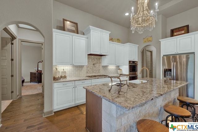 kitchen with a kitchen island with sink, white cabinetry, dark wood-type flooring, and decorative light fixtures