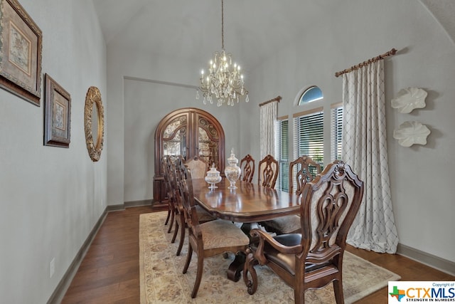 dining space featuring hardwood / wood-style flooring, a chandelier, and vaulted ceiling