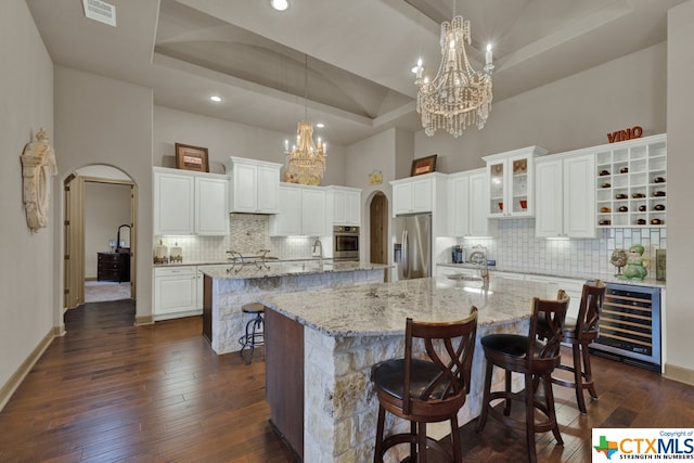 kitchen featuring stainless steel appliances, wine cooler, a large island with sink, a kitchen breakfast bar, and white cabinets