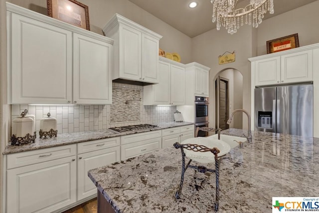 505 Cantera Rdg, New Braunfels, TX 78132 - kitchen with stainless steel appliances, white cabinetry, backsplash, arched walkways, and recessed lighting