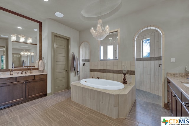 bathroom featuring independent shower and bath, vanity, and an inviting chandelier