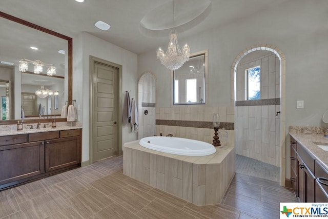 505 Cantera Rdg, New Braunfels, TX 78132 - bathroom featuring a chandelier, two vanities, a bath, a walk in shower, and recessed lighting