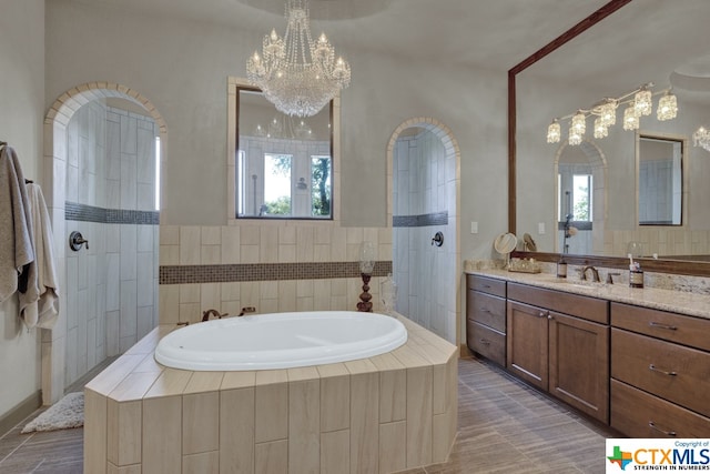 bathroom featuring vanity, independent shower and bath, plenty of natural light, and an inviting chandelier