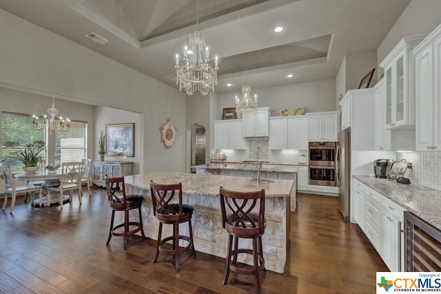 kitchen featuring a breakfast bar, a raised ceiling, a large island, and dark hardwood / wood-style flooring