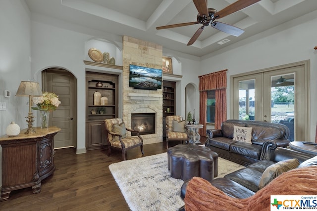 living room with built in shelves, a fireplace, beam ceiling, dark wood-type flooring, and ceiling fan