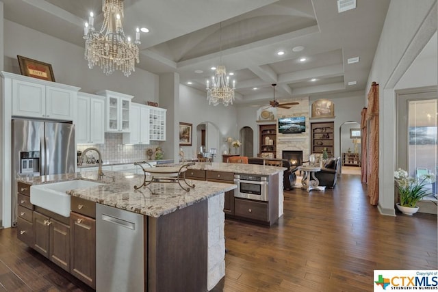 505 Cantera Rdg, New Braunfels, TX 78132 - kitchen featuring arched walkways, a kitchen island with sink, a sink, ceiling fan, and a chandelier