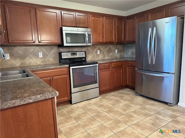 kitchen with sink, decorative backsplash, light tile patterned floors, and stainless steel appliances