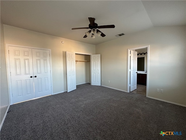 unfurnished bedroom featuring multiple closets, dark colored carpet, lofted ceiling, and ceiling fan