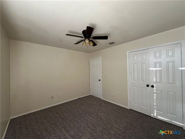 unfurnished room featuring a textured ceiling, dark colored carpet, and ceiling fan