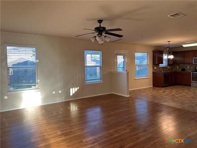 unfurnished living room featuring ceiling fan with notable chandelier, sink, and dark hardwood / wood-style flooring