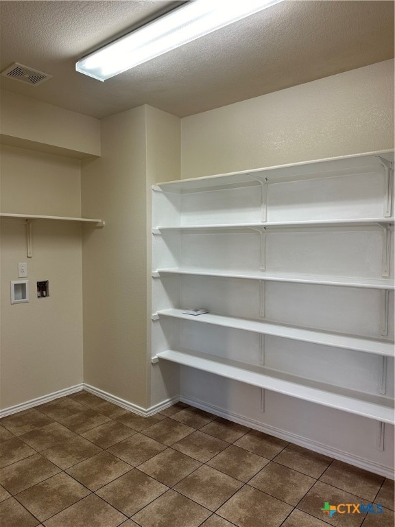 laundry room with a textured ceiling, hookup for a washing machine, and dark tile patterned floors