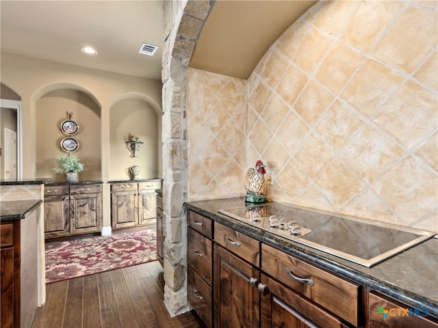 kitchen with black electric stovetop, dark hardwood / wood-style flooring, and dark stone counters