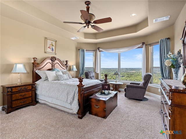 carpeted bedroom with ceiling fan and a tray ceiling