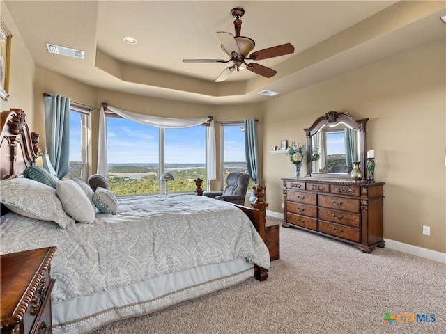 carpeted bedroom featuring a tray ceiling and ceiling fan