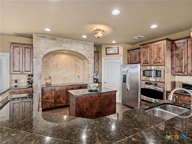 kitchen with decorative backsplash, a center island, sink, and appliances with stainless steel finishes