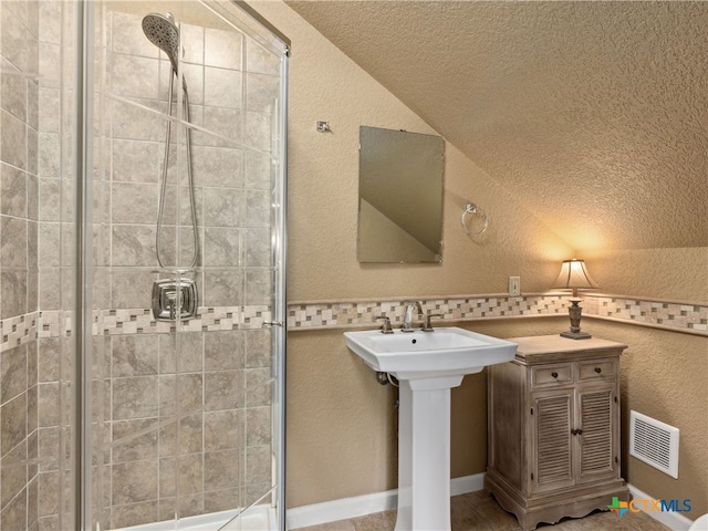 bathroom with sink, lofted ceiling, and a shower with door