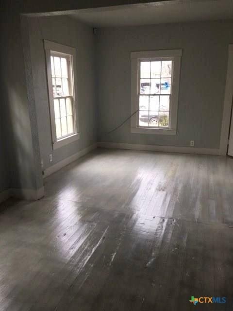 empty room featuring baseboards, a wealth of natural light, and wood finished floors