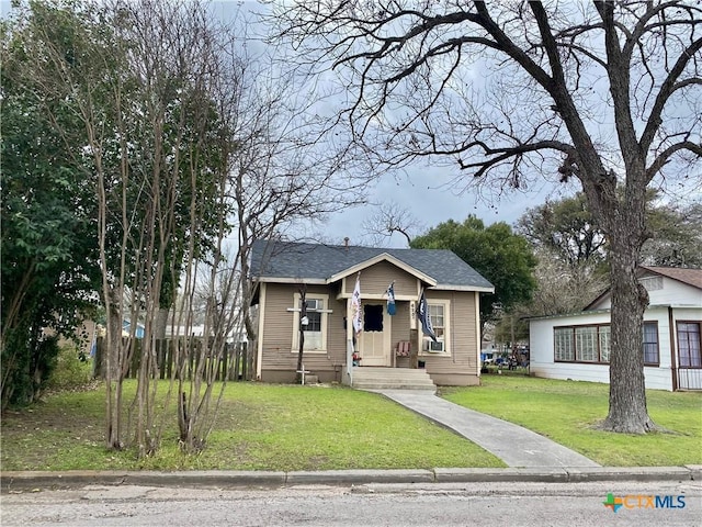 bungalow featuring a front lawn and a shingled roof