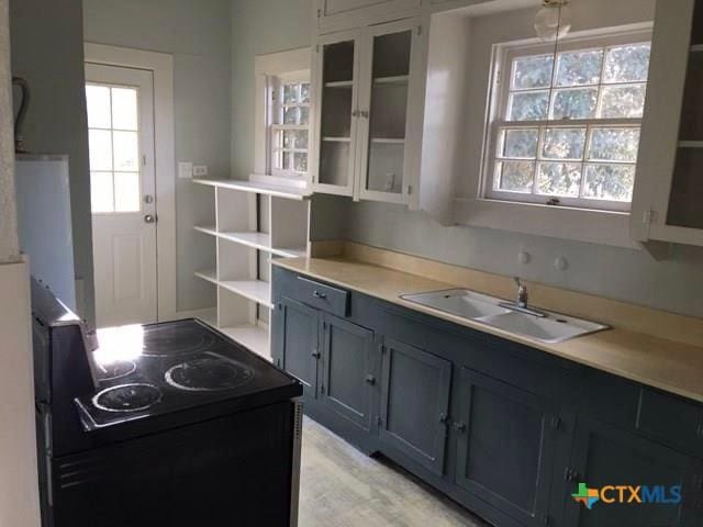 kitchen with a wealth of natural light, electric range, open shelves, and a sink