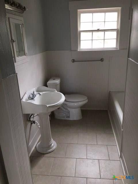 bathroom with a bath, tile patterned flooring, and toilet