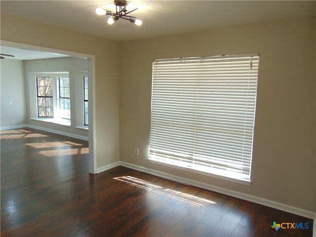 empty room featuring a chandelier and dark hardwood / wood-style flooring