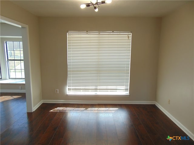 unfurnished room featuring dark hardwood / wood-style floors and a notable chandelier