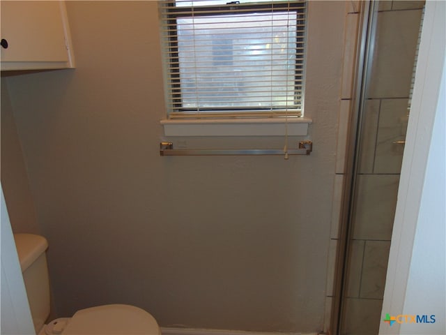 bathroom with toilet and a shower with shower door