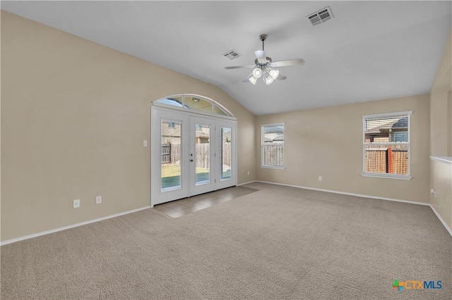 carpeted spare room featuring vaulted ceiling, ceiling fan, french doors, and visible vents