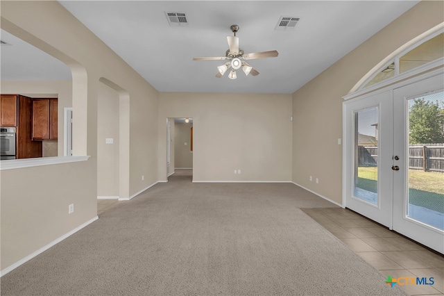 spare room featuring ceiling fan, light carpet, and french doors