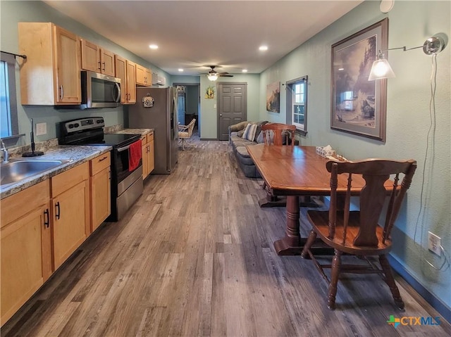 kitchen featuring light brown cabinetry, sink, wood-type flooring, hanging light fixtures, and stainless steel appliances