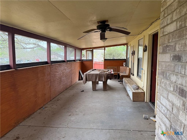 sunroom featuring a ceiling fan, unfinished concrete flooring, and billiards