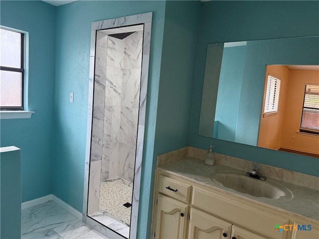 bathroom with marble finish floor, vanity, a marble finish shower, and baseboards