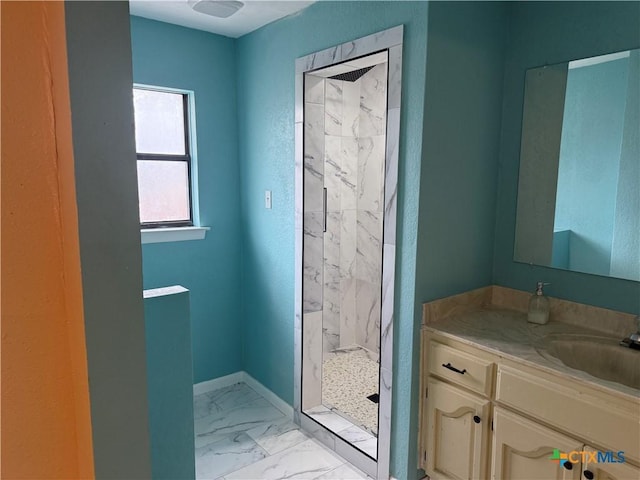 bathroom with marble finish floor, baseboards, vanity, and a marble finish shower
