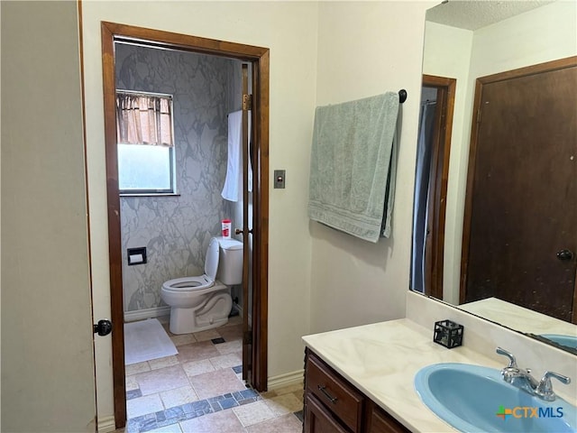 bathroom featuring baseboards, toilet, and vanity