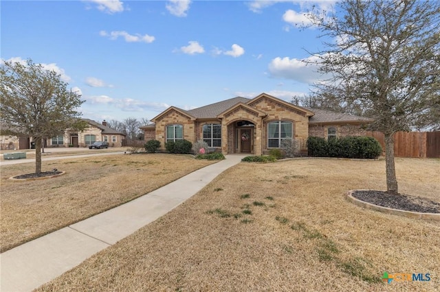 ranch-style home with a front lawn, fence, and brick siding